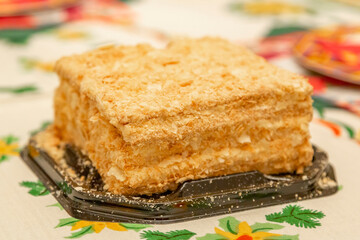 Layered cake Napoleon according to the French recipe. Made at home with crispy baked goods, butter cream and pastry crumbs