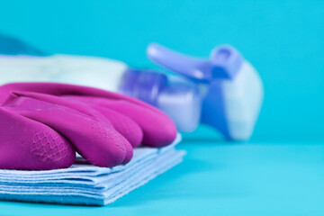 Microfiber rags with latex gloves and sprayer on a blue background. Cleaning products and supplies concept. Selective focus.