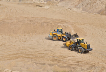 Obraz premium Wheel loader working at the sand open pit. Quarry in which sand and gravel is excavated from the ground. Mining industry.