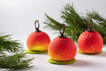 Three mousse desserts in the form of Christmas balls on white background. New Year party.