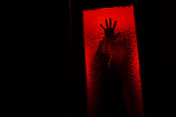 A hand in the dark behind the glass.