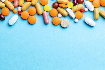 assorted pills and tablets top border over blue background. above view. pharmaceutical concept