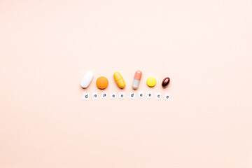 words dependence near assorted pills over pink background. creative medicine and drug concept. drug dependence conceptual