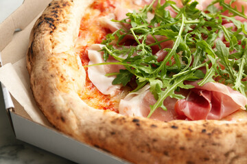 Tasty pizza with meat and arugula in cardboard box, closeup