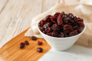 Dried cranberries in bowl on light table, closeup