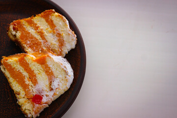Two pieces of pumpkin cheesecake standing on a clay plate on a white background