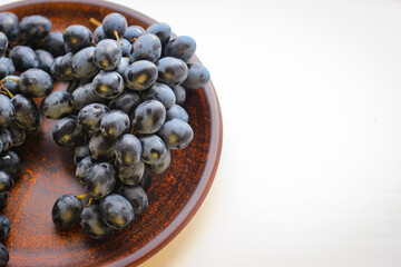 Blue grapes on a clay plate with copy space