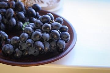 Blue grapes on a clay plate with copy space