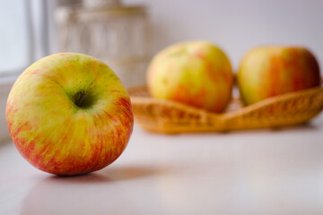 A few ripe apples on a white surface. Rear background is blurred