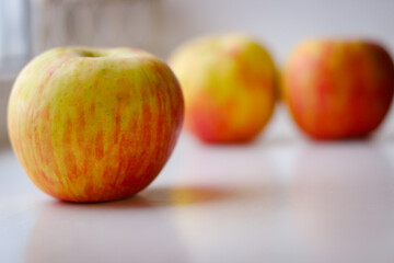 A few ripe apples on a white surface. Rear background is blurred