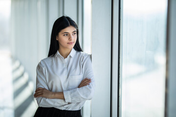 Young businesswoman crossed hands portrait in office with panormic windows.
