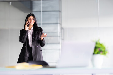 Young smiling business woman talking on the phone in office