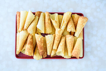Norwegian Krumkake cookies on a red tray on a light white and gold background
