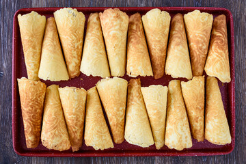 Norwegian Krumkake cookies on a red tray on a rustic dark wood table
