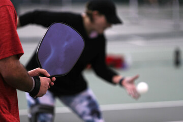 A woman serves during a mixed doubles pickleball match.