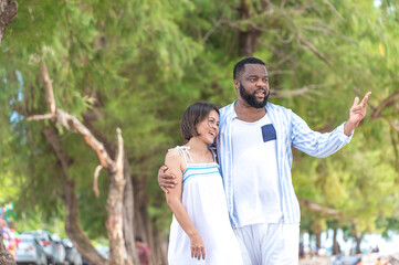 Happy Afircan American Black man hug Asia Woman lover honeymoon time on sea beach - outdoors summer beach concept