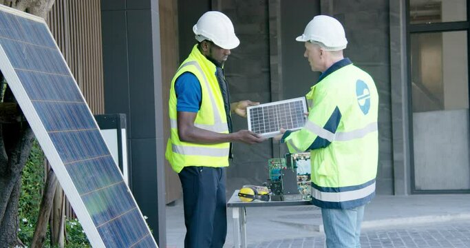 2 Electric solar panel industry engineers instructor and trainee teaching discussion with coworker teamwork about photovoltaic solarium electricity technology prototype business  