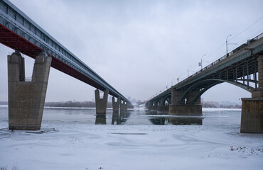 Photo of the frozen Ob River with road and subway bridges on a winter snowy day. Novosibirsk, Russia.