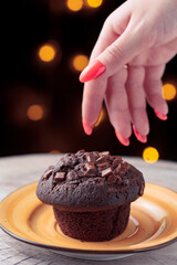 hand reaches for delicious chocolate cake on yellow plate