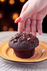 hand reaches for delicious chocolate cake on yellow plate