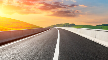 Naklejka premium Asphalt road and mountain with tea plantation at sunset.Road and mountain background.