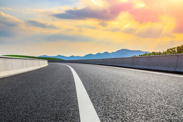 Naklejka premium Asphalt road and mountain at sunset.Road and mountain background.