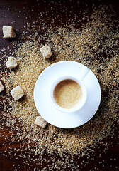 Cup of coffee and brown sugar on wooden background. Top view. 