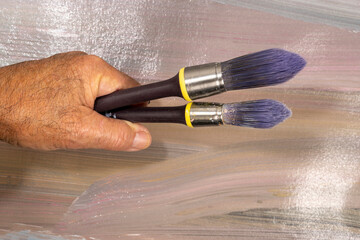 Two round brushes against a painted canvas