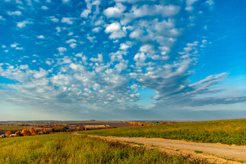 Rural landscape with fields, roads, woodland and the blue sky with various clouds