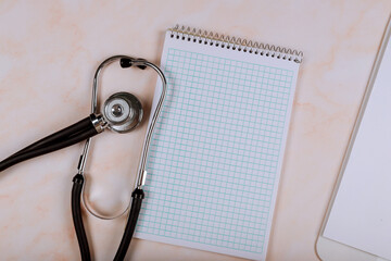Fototapeta na wymiar Stethoscope on work desk of doctor in hospital with medical blank notebook