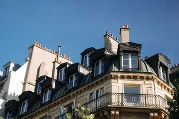 Fototapeta na wymiar Antique roof with chimneys and dormers on a house with balconies in the historic center of Paris.