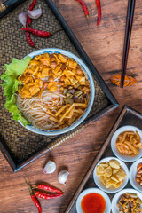 A bowl of Liuzhou river snails rice noodle on a wooden table