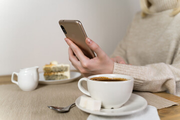 The phone is in hand, and next to it is a mug of coffee and a cake