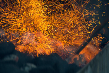 Bright sparks from glowing embers. Heat in the barbecue grill. Defocused photo.