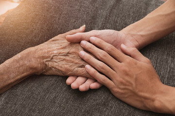 Fototapeta premium A person holding a hand An old woman lying in bed sick.
