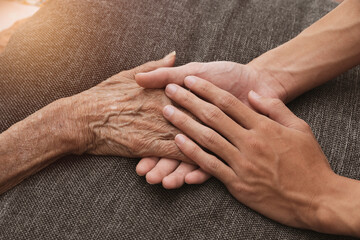 A person holding a hand An old woman lying in bed sick.