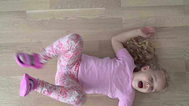 Emotion active girl child lying on floor move and shout. Gimbal motion shot