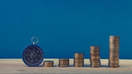 Compass and gold coin over blue background.