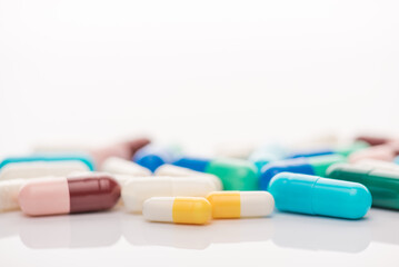 Close up view photo of pile heap stack of multicolored pills and tablets without packing lying on white table desk