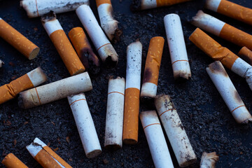 Cigarettes buds with ashtray on dark background.
