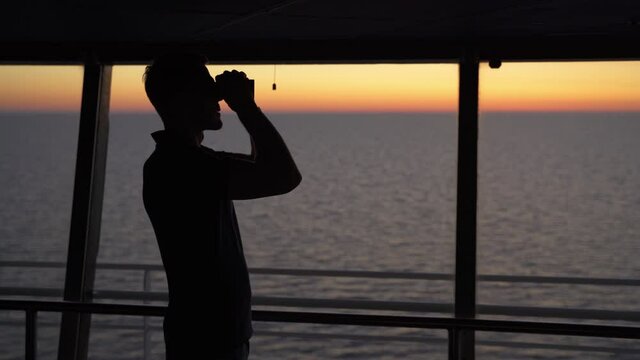 Navigation officer on lookout on ferry bridge during sunset, medium shot