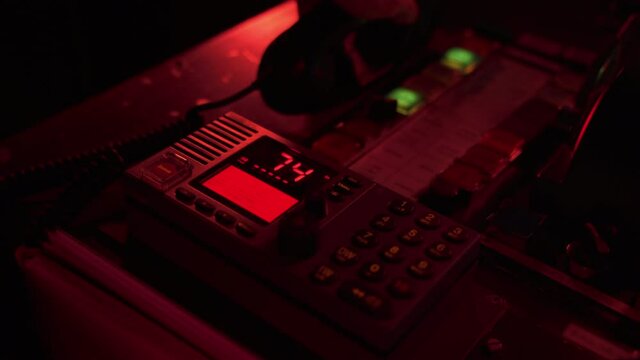 VHF radio being operated by navigation officer on ship at night, close up