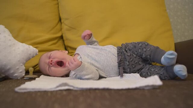 Baby yawning expression while sleeping lied down on a blanket bed, side shot, close-up, isolated