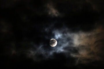 The Moon behind the clouds. The moon in a partially clouded colorful sky.