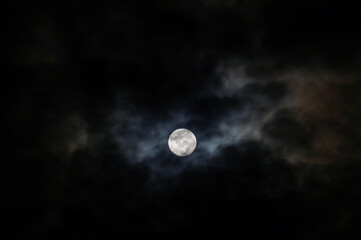 The Moon behind the clouds. The moon in a partially clouded colorful sky.
