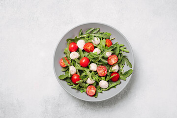 Diet and healthy salad with arugula, cherry tomatoes, mozzarella cheese on white background