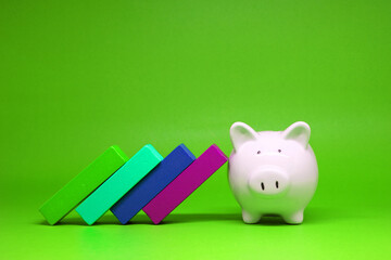 Domino effect with Strong Piggy bank isolated on green background with copy space for text message - Strong of Fund Investment , Saving money - green concept of Stable Banking and financial  concept 