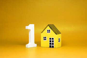First House , Number 1 ( one ) with wooden home Isolated yellow Background and Copy Space - House property  Business building and finance loan Concept