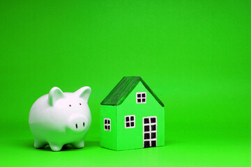 Fund , Investment , Saving money concept : Mockup White Piggy bank and House on green background...