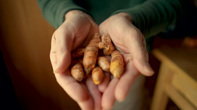 Man holding fresh turmeric root in his hands showing them to the camera